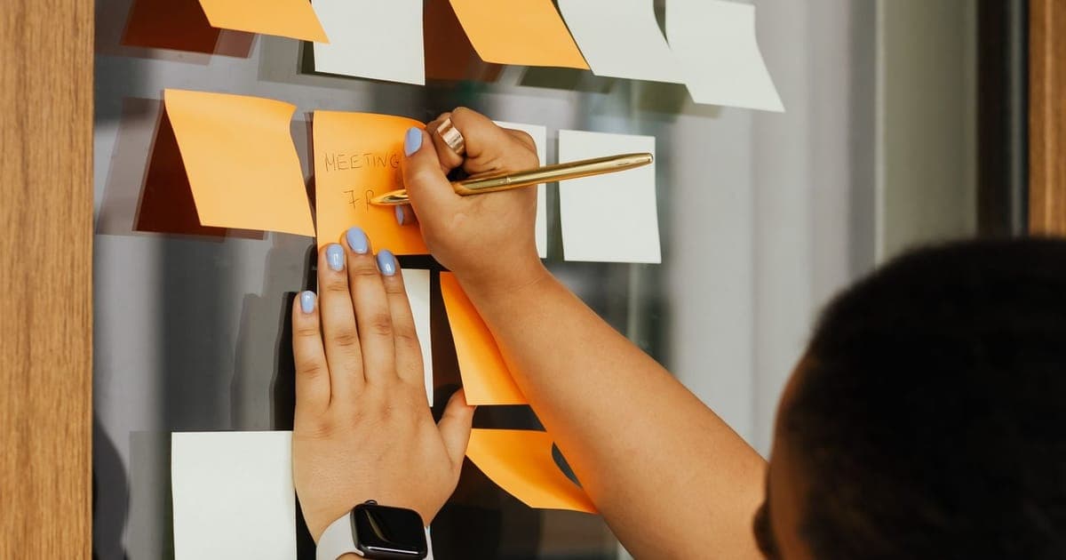 Project lead building a board of sticky notes on a glass wall
