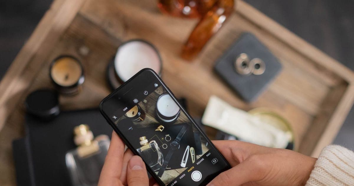 Hands photographing a flat lay of products on a phone